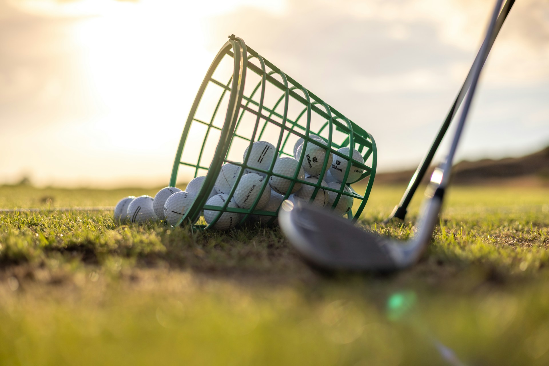 Golf iron and practice balls at sunset on the driving range